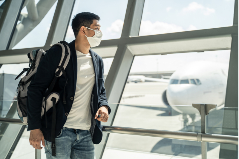 traveler in airport with backpack and face mask